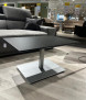Couchtisch 1426-MMN-EST aus modernem schwarzem MDF/HPL, höhenverstellbar, mit Metallgestell, neben einem grauen Sofa.