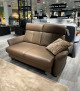 Sitzgruppe Mondo Comfort Evado mit beigem, geripptem Kissen, abgebildet in einem Ausstellungsraum neben anderen Sofas und Einrichtungsgegenständen.