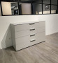 Die Kommode „Monda Design Ajana Scale“ mit vier Schubladen steht auf einem hellen Holzboden vor einer weißen Wand.