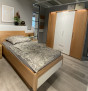 Modernes Schlafzimmer mit dem „Mondo Comfort Plus“-Schlafzimmer-Set von Komfort, gemusterter Bettwäsche, einem Kleiderschrank und Wanddekoration.