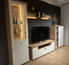 Modernes Wohnzimmer mit der Wohnwand „Vito Idamo“ im Dekor „Alteiche“, „Tonweiß“ matt, Fernseher, Vitrine, Regale, Holzboden.
