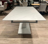 Ausziehbarer Esstisch „Bern“ in weißer Keramikoptik mit Säulenfuß, im Showroom zusammen mit Stühlen ausgestellt.