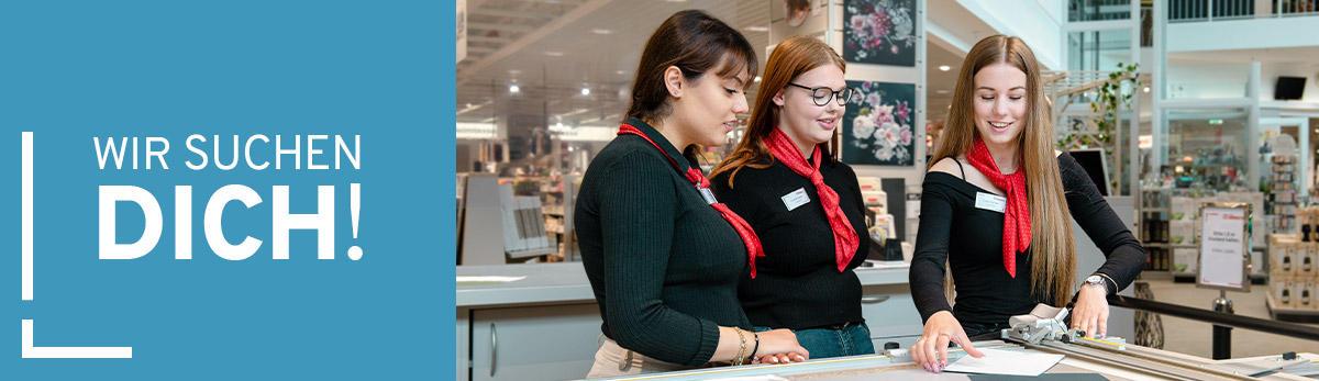 Auszubildende zeigt Kolleginnen den Zuschnitt von Hintergrundkartons für Bilderrahmen