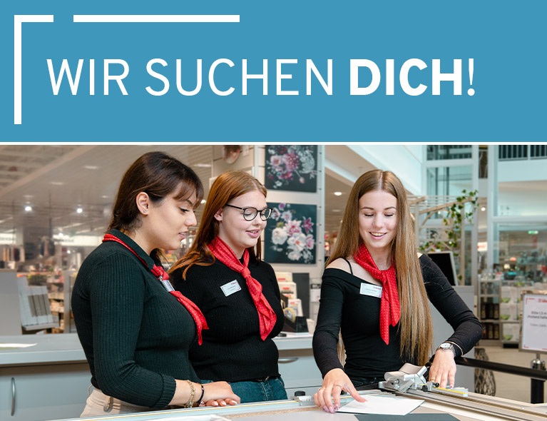 Auszubildende zeigt Kolleginnen den Zuschnitt von Hintergrundkartons für Bilderrahmen