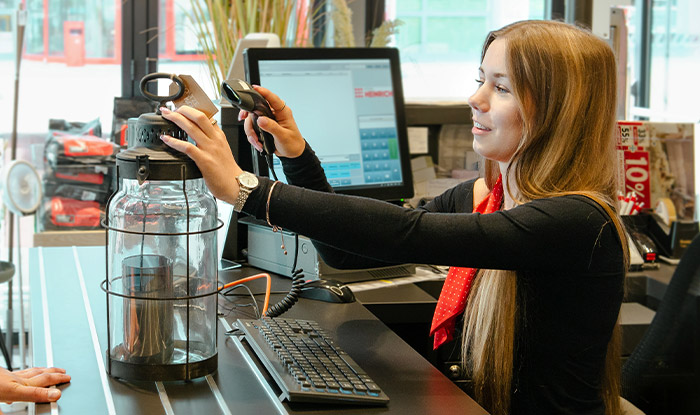 Mitarbeiterin scannt die Auswahl der Kundin an der Kasse