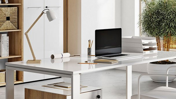 Moderner weißer Schreibtisch mit Glasplatte, Laptop, Schreibtischlampe und Büroorganizer in hellem Arbeitszimmer