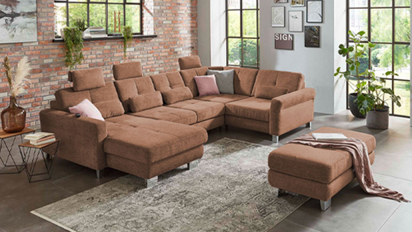 Wohnlandschaft in U-Form mit mehreren Sitz- und Liegeflächen, passendem Hocker und Kissen in einem loftartigen Wohnzimmer
