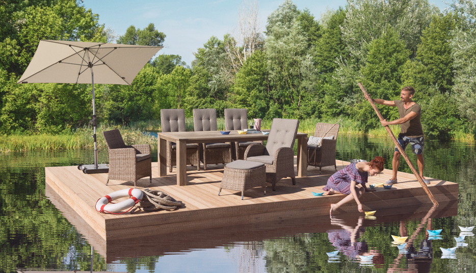 Schwimmende Terrasse mit Gartenmöbeln, Sonnenschirm und Familie auf einem See