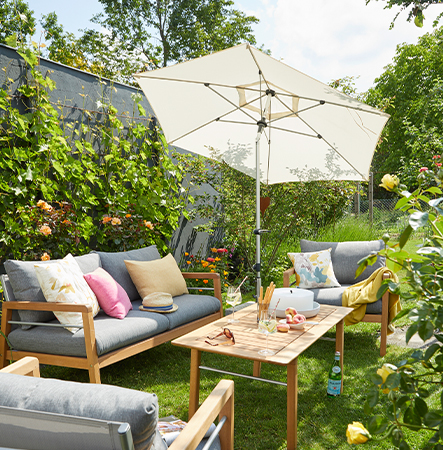 Großer Gartensonnenschirm über einer modernen Lounge-Sitzgruppe im Garten