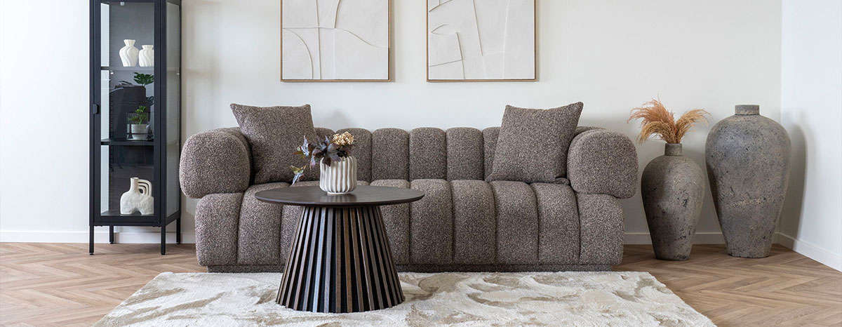 Helles Wohnzimmer mit dunkelgrauen Sofa, schwarzen Couchtisch und Vitrine