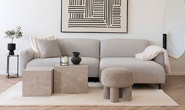 Helles Wohnzimmer mit cremefarbenen Sofa, Marmor-Couchtischen und Stoffhocker