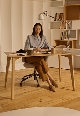 Frau arbeitet am Stressless Bordeaux Tisch auf einem Stressless Laurel Home Office Stuhl.