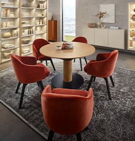 Esszimmerstühle mit rotem Stoffbezug und schwarzen Beinen an einem runden Holztisch