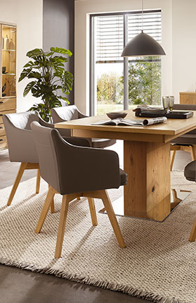 Esszimmer mit braunen Polsterstühlen und Holztisch mit Fußsäule